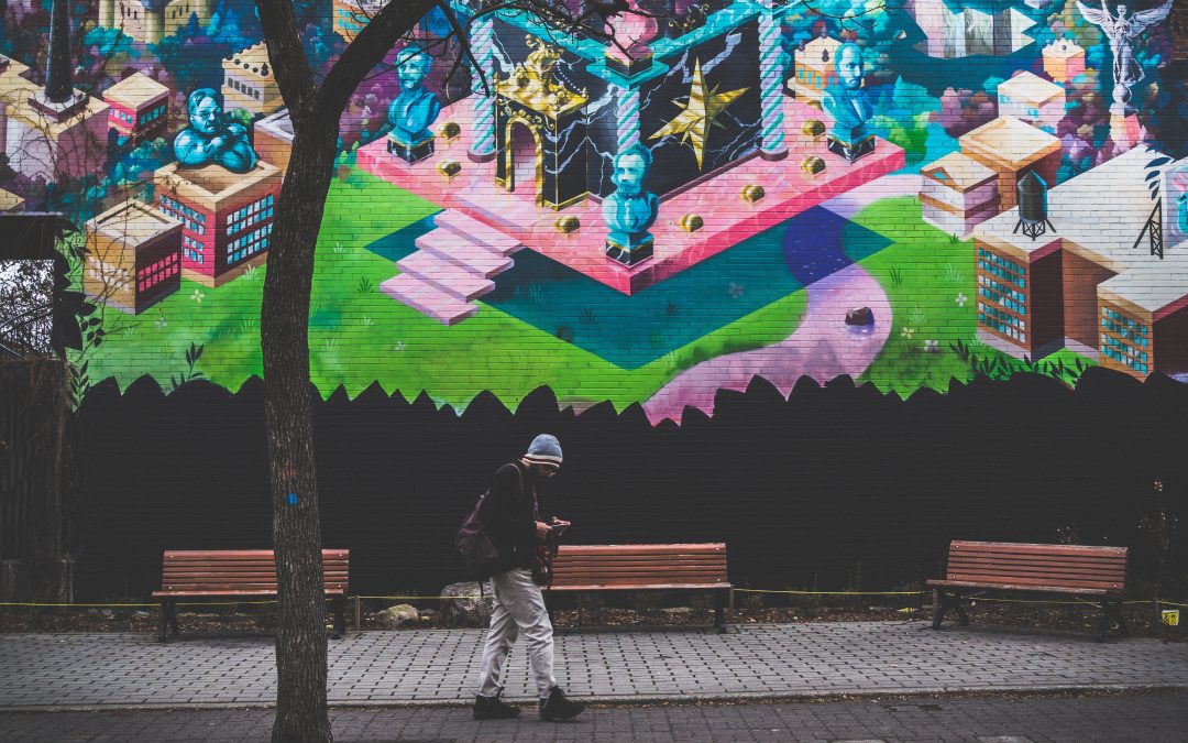 Ragazzo che cammina davanti ad un murales