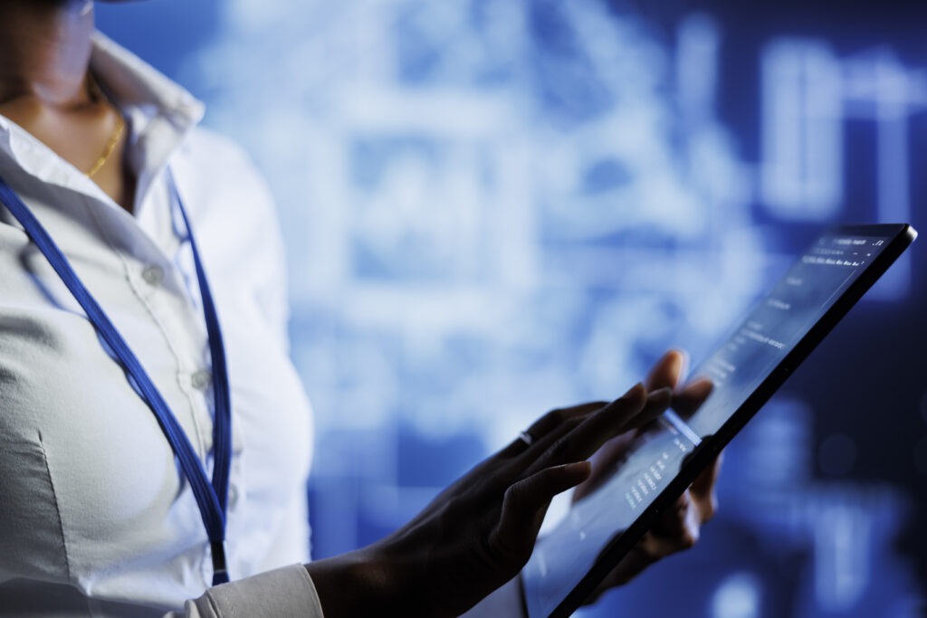 Donna vestita con una camicia bianca che sta tenendo in mano un tablet con una serie di dati al suo interno.