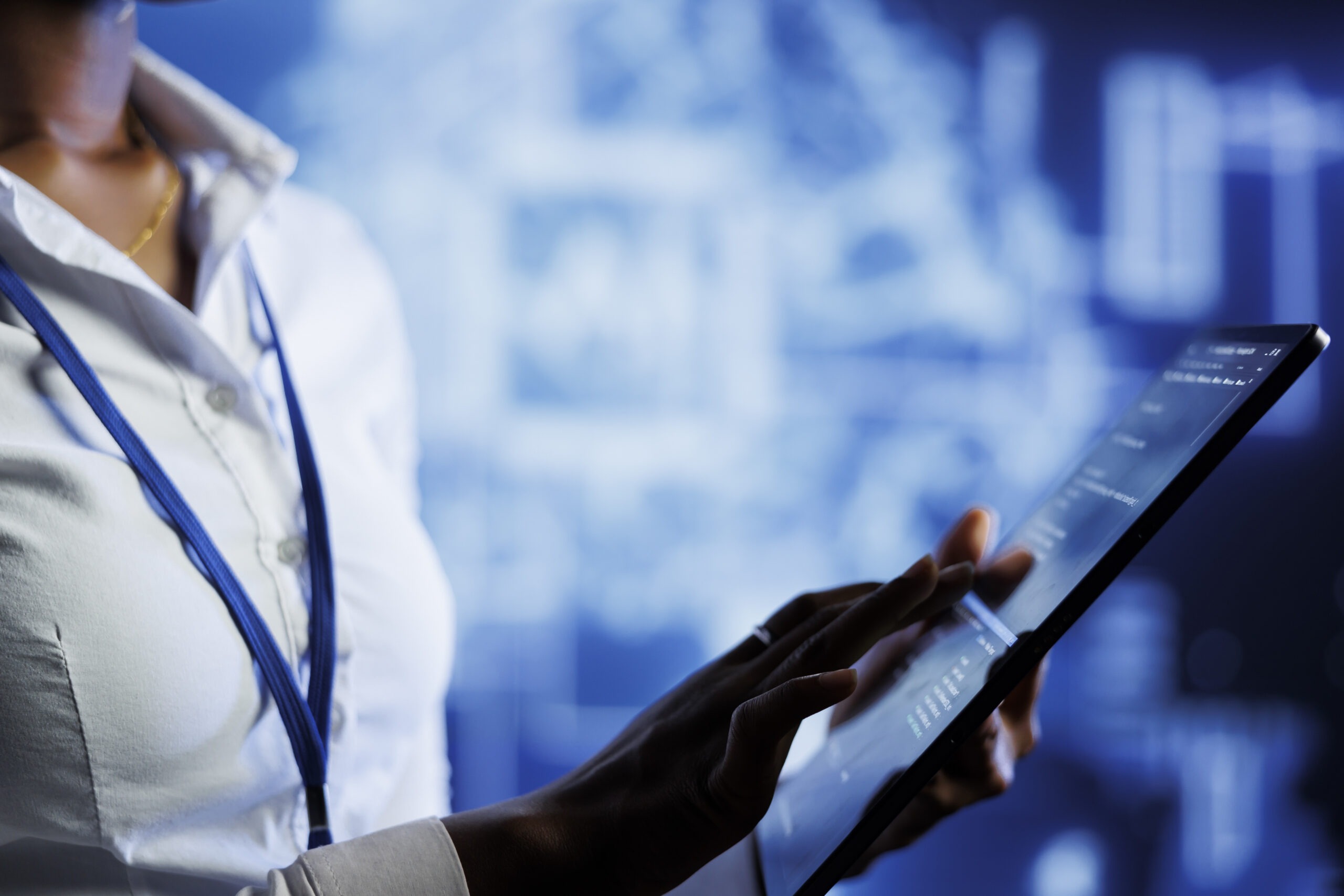 Donna vestita con una camicia bianca che sta tenendo in mano un tablet con una serie di dati al suo interno.