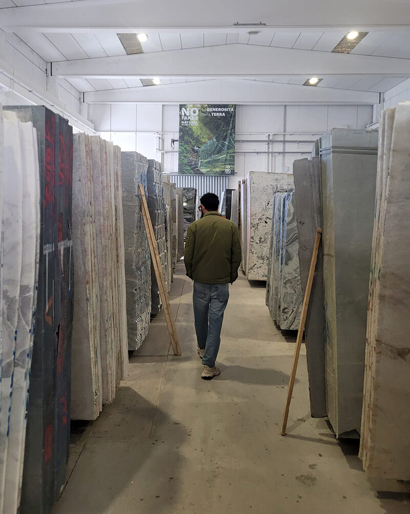 persona camminando lungo una fila di lastre di marmo esposte presso lo stabilimento produttivo dell'azienda big graniti